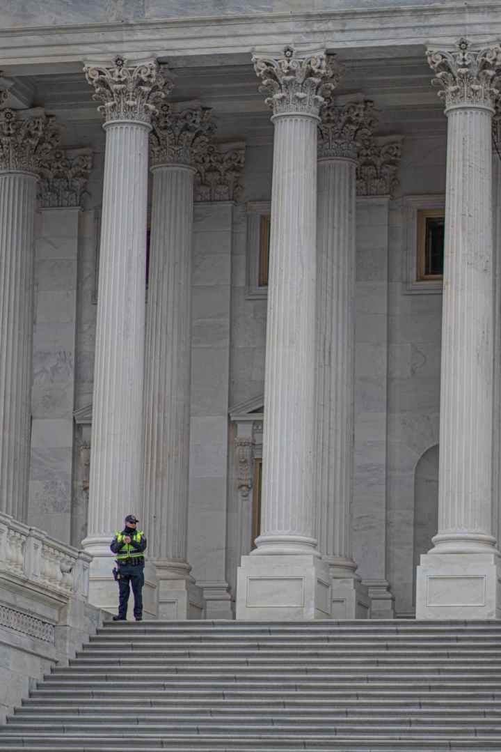 a police officer standing near white concrete pillars of a building